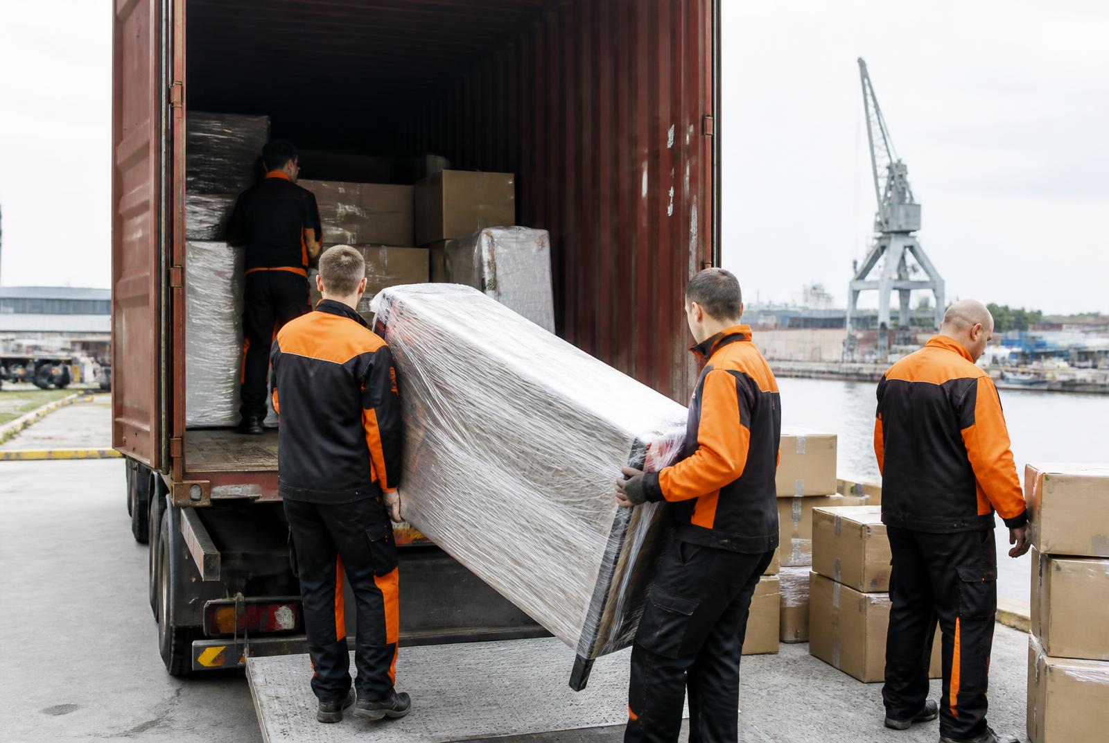 Equipe carregando móveis embalados e caixas em contêiner no porto